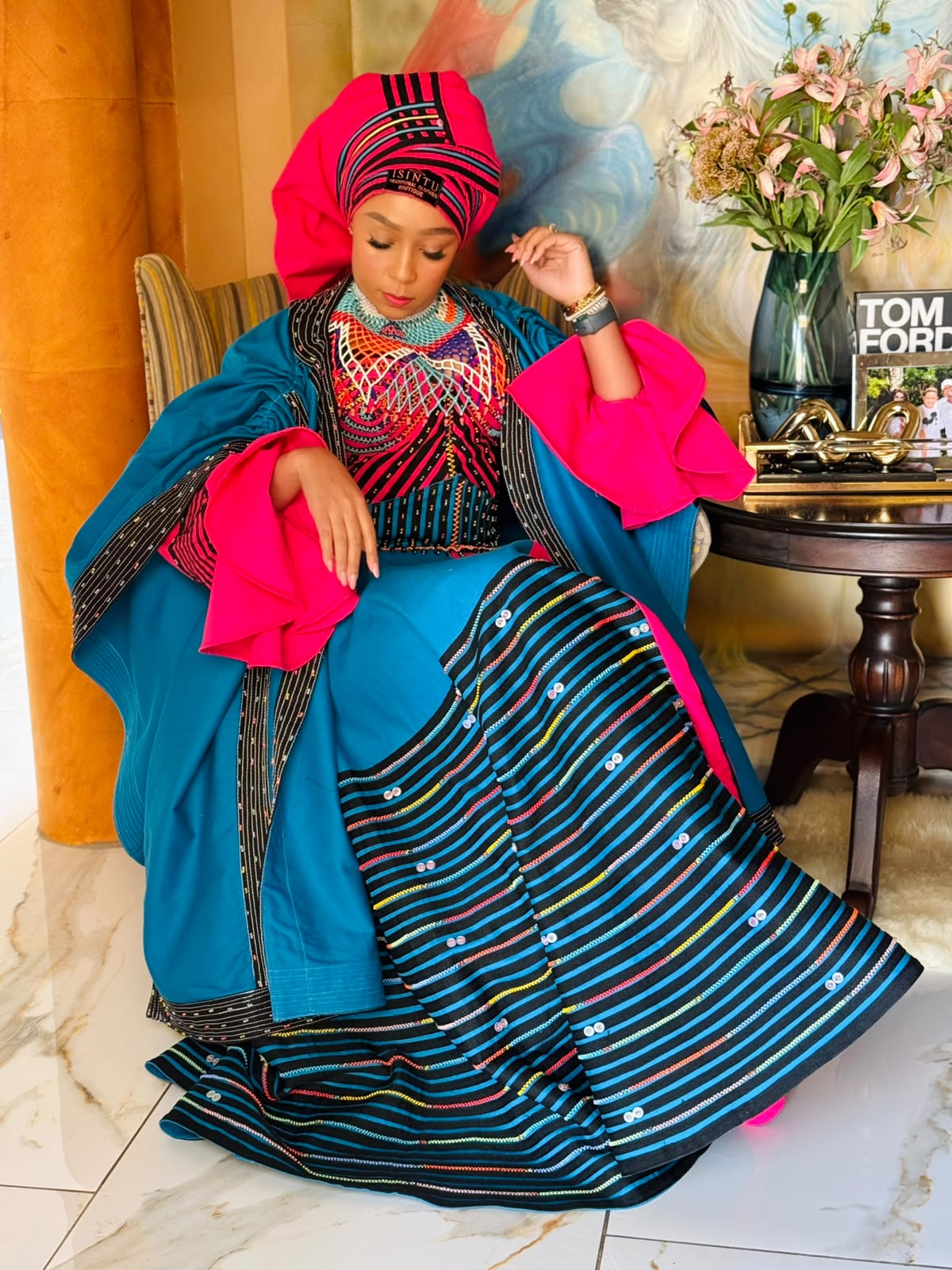 Buli seated in teal and pink ensemble